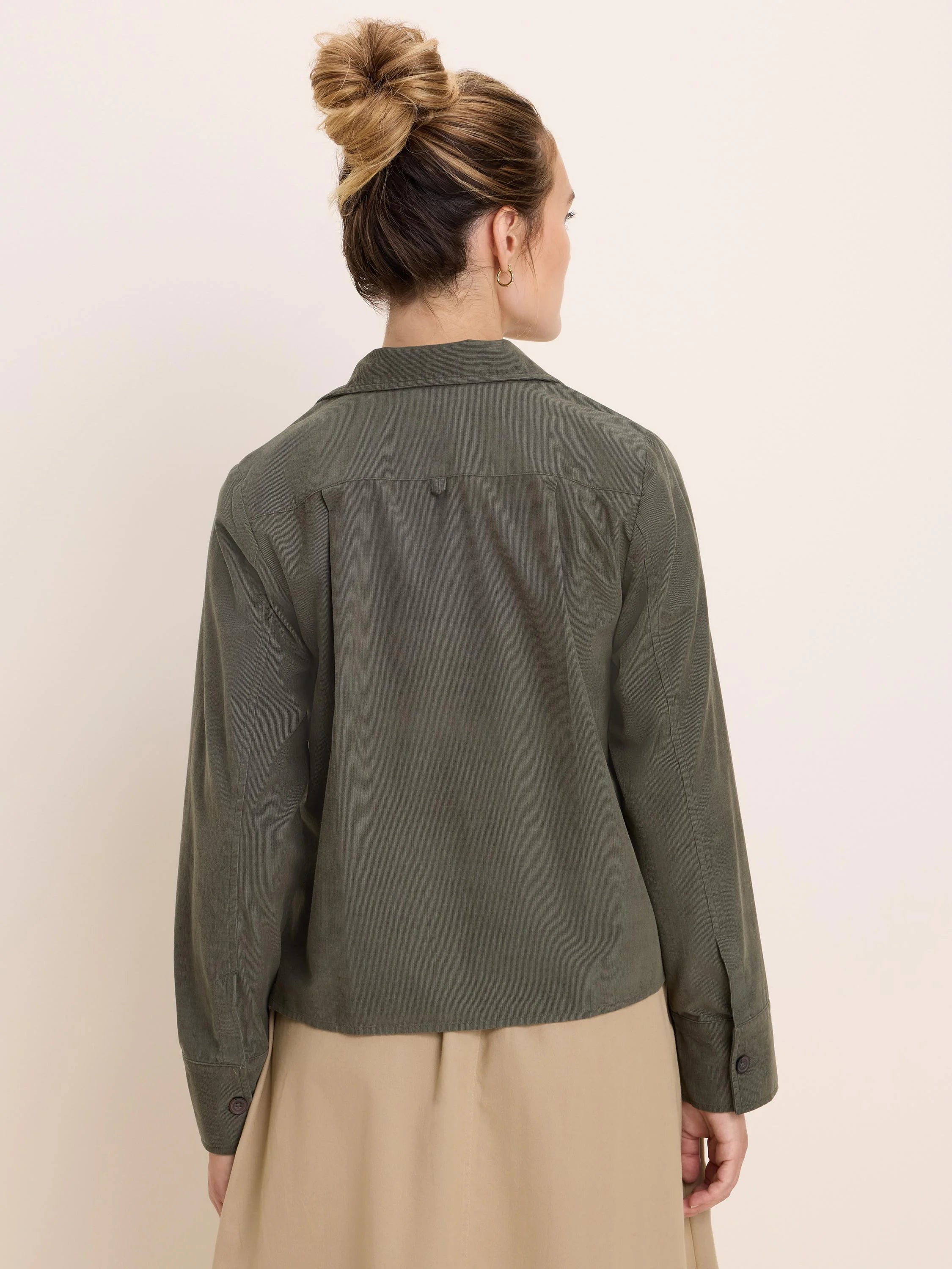 Deep olive green baby cord shirt jacket, seen from behind. Collared, long sleeves, fine vertical textured fabric.