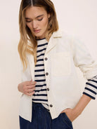 Cream baby cord shirt jacket with a collar, single chest pocket, and dark buttons.