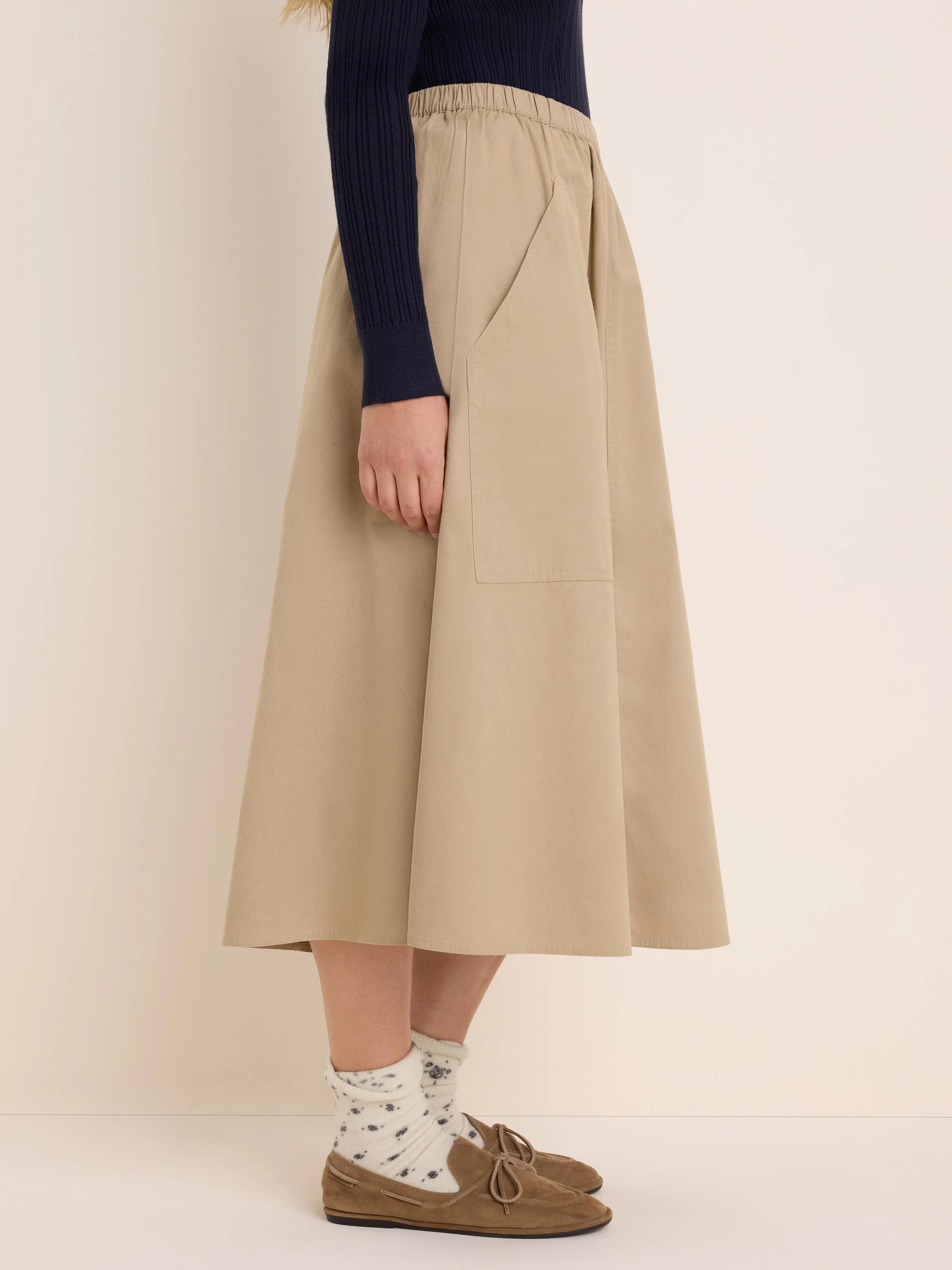 Beige twill cargo skirt. Features an elastic waist, an A-line cut, and a large side patch pocket.