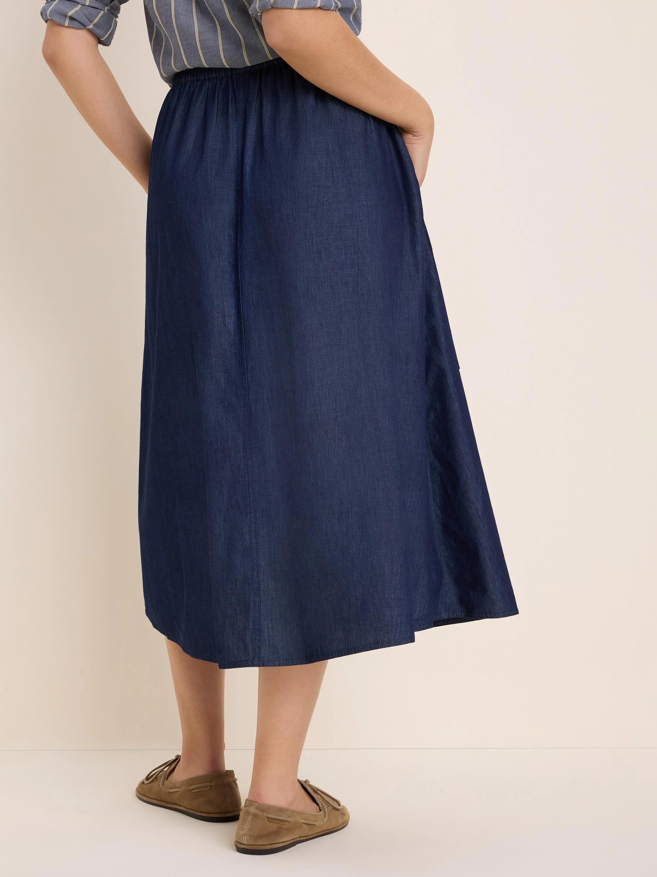 Dark blue drapey denim midi skirt with elastic waist and a flowing A-line cut.