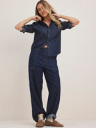 Dark blue wide-leg denim pants with a drawstring waist, prominent front patch pockets, and rolled-up cuffs.