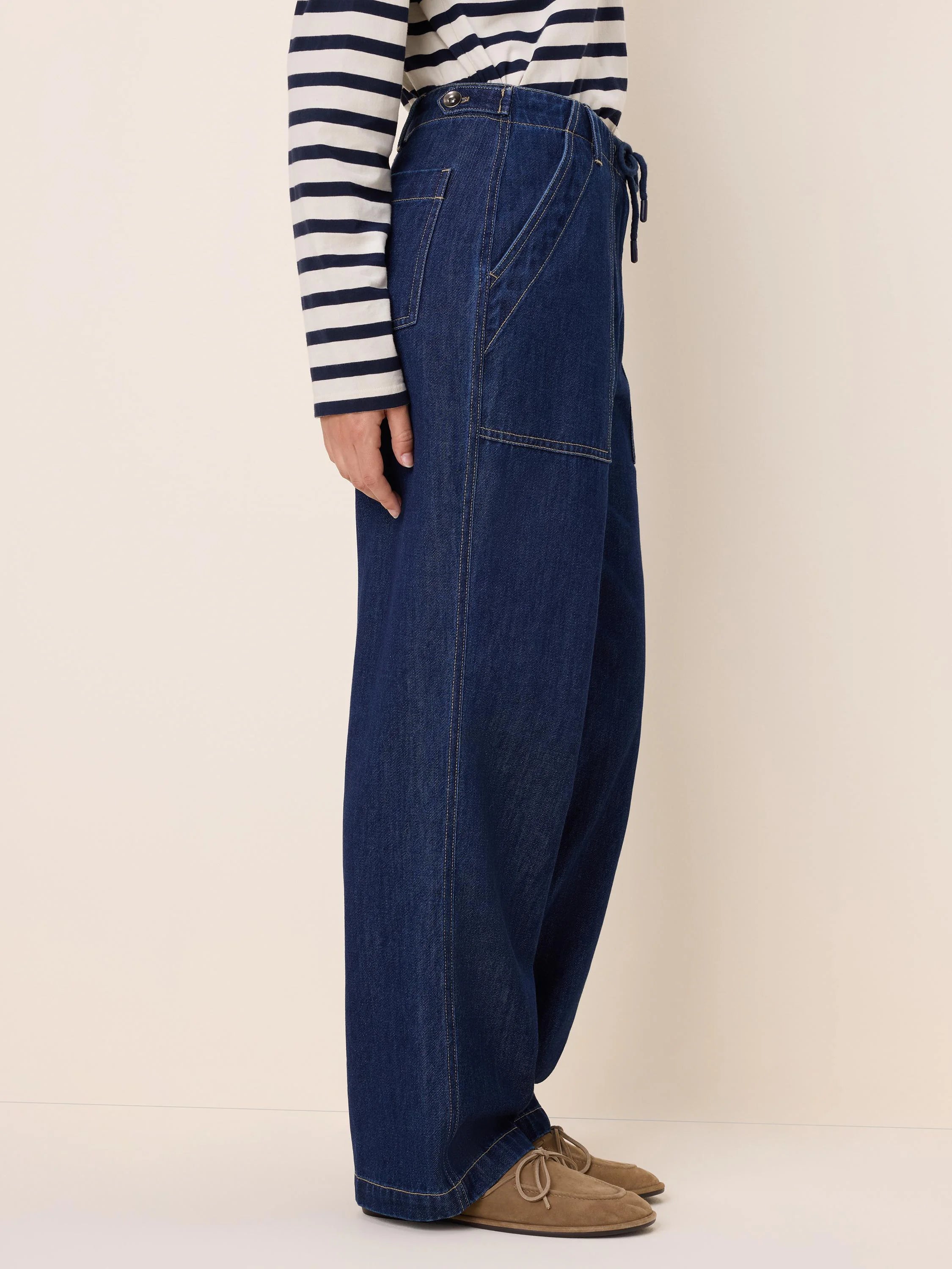 Dark indigo wide-leg denim pants with a drawstring waist, button closure, and light contrast stitching.