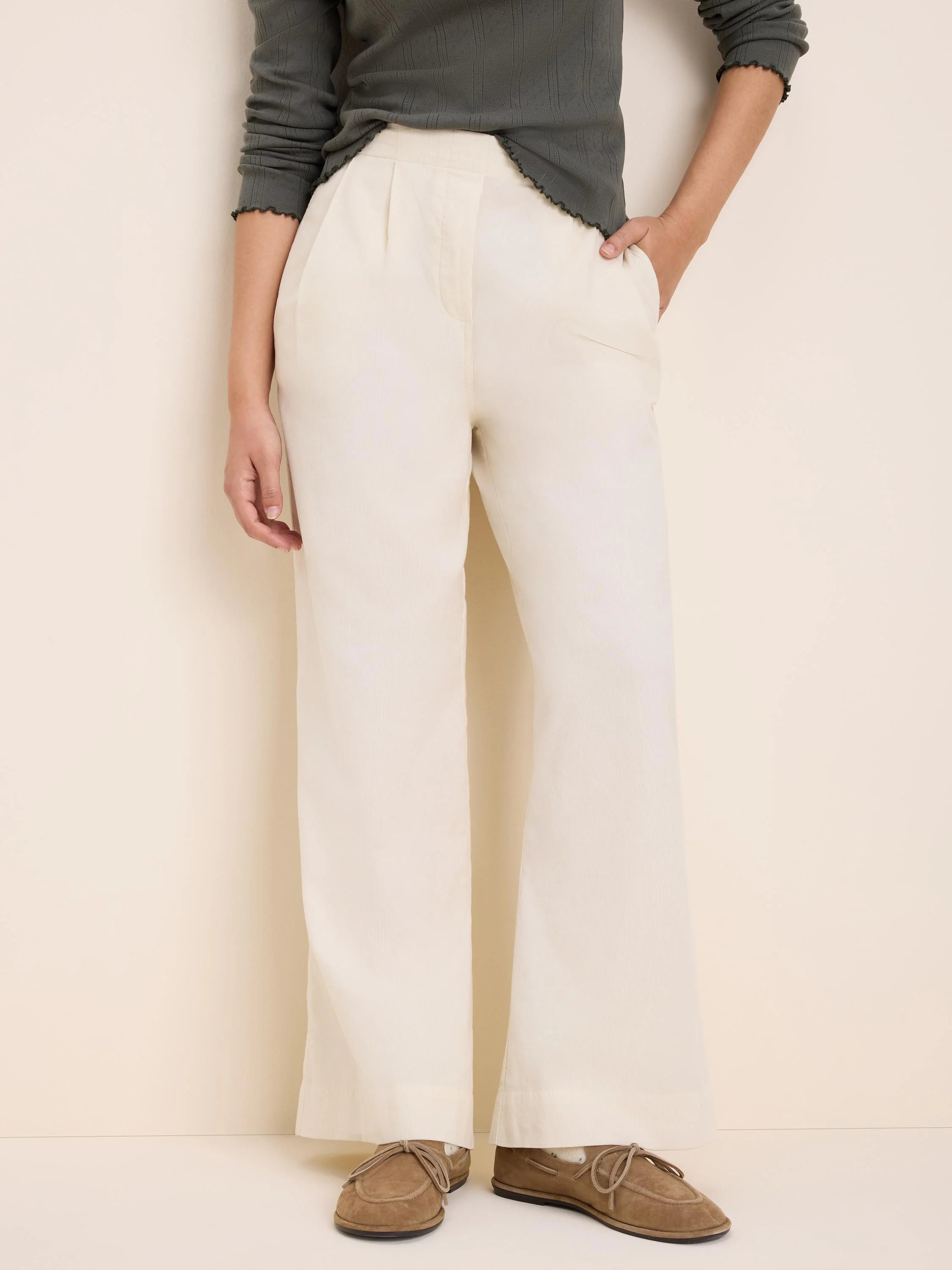 Cream baby corduroy pants, high-waisted with front pleats and wide legs.