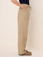 Khaki drawstring twill pants with a wide leg. Features a front slash pocket, side patch pocket, and a button closure.