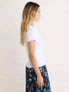 White pointelle rib knit tee with ruffled short sleeves and hem.