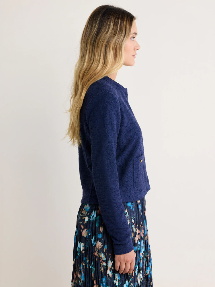 Navy blue, collarless, textured knit bomber jacket with a small front pocket and a button.
