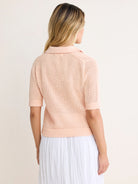 Light peach open-knit polo sweater with short sleeves, ribbed collar, cuffs, and hem. Shown from the back.