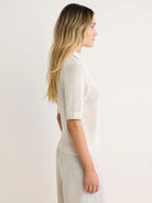 Cream mesh polo sweater with a ribbed collar, short sleeves, and ribbed hem.