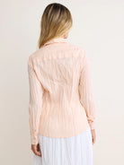 Pale peach long-sleeve cotton shirt with a distinct crinkled texture, shown from the back.