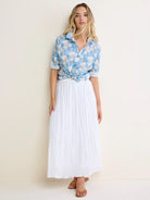 Blue crinkled cotton shirt with cream floral pattern, button-down, rolled sleeves, tied at waist.