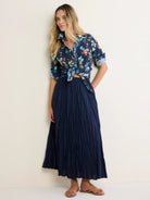 Navy cotton button-up shirt with blue/peach floral print, tied at waist, rolled sleeves. Features a crinkled texture.