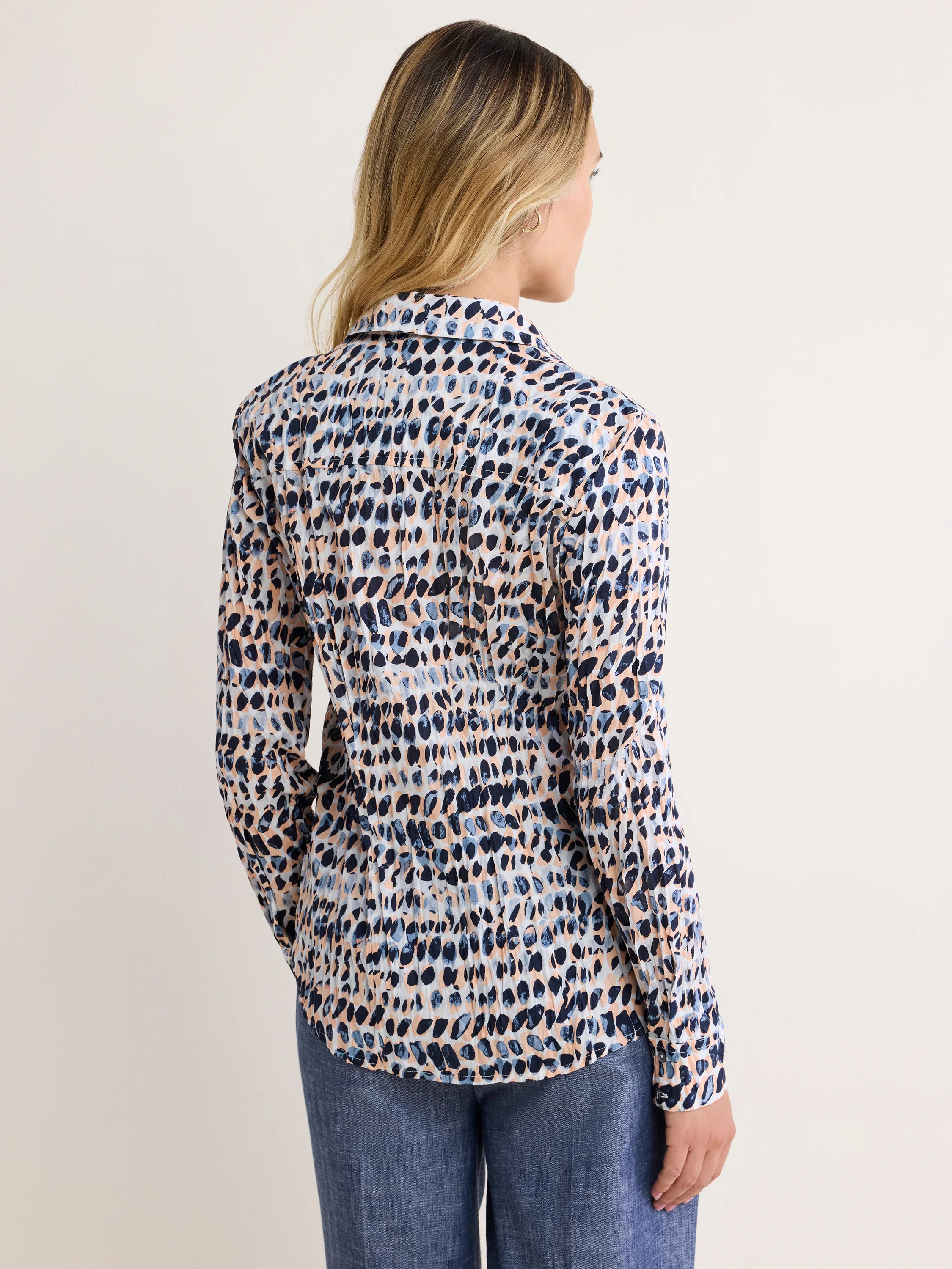 Back of collared long-sleeve shirt: cream with irregular navy, light blue, and peach spots.