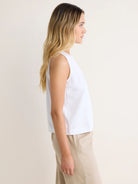 White sleeveless tank top with a high neck and relaxed fit, shown on a model in profile.