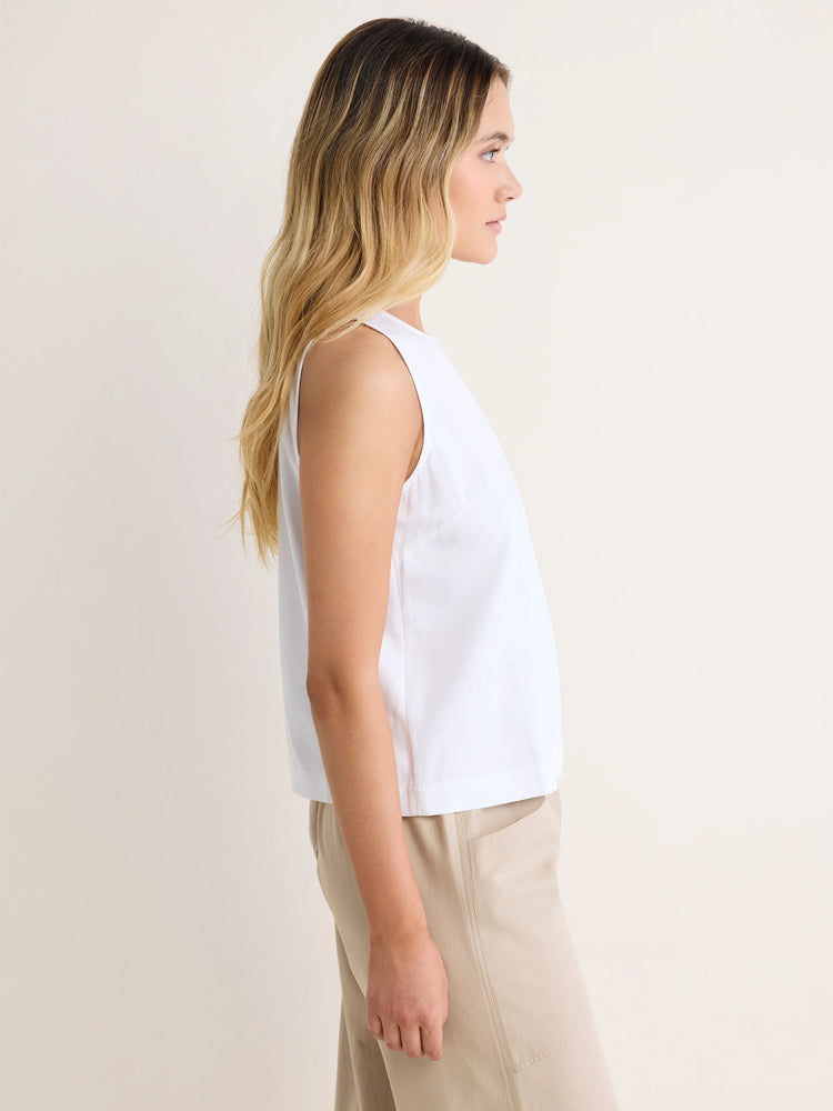 White sleeveless tank top with a high neck and relaxed fit, shown on a model in profile.