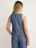 Back view: Blue chambray sleeveless tank with a round neck, keyhole & button closure, and visible slub texture.