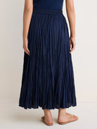 Dark blue cotton crinkle maxi skirt with prominent vertical texture & elastic waist, worn by a model from behind.