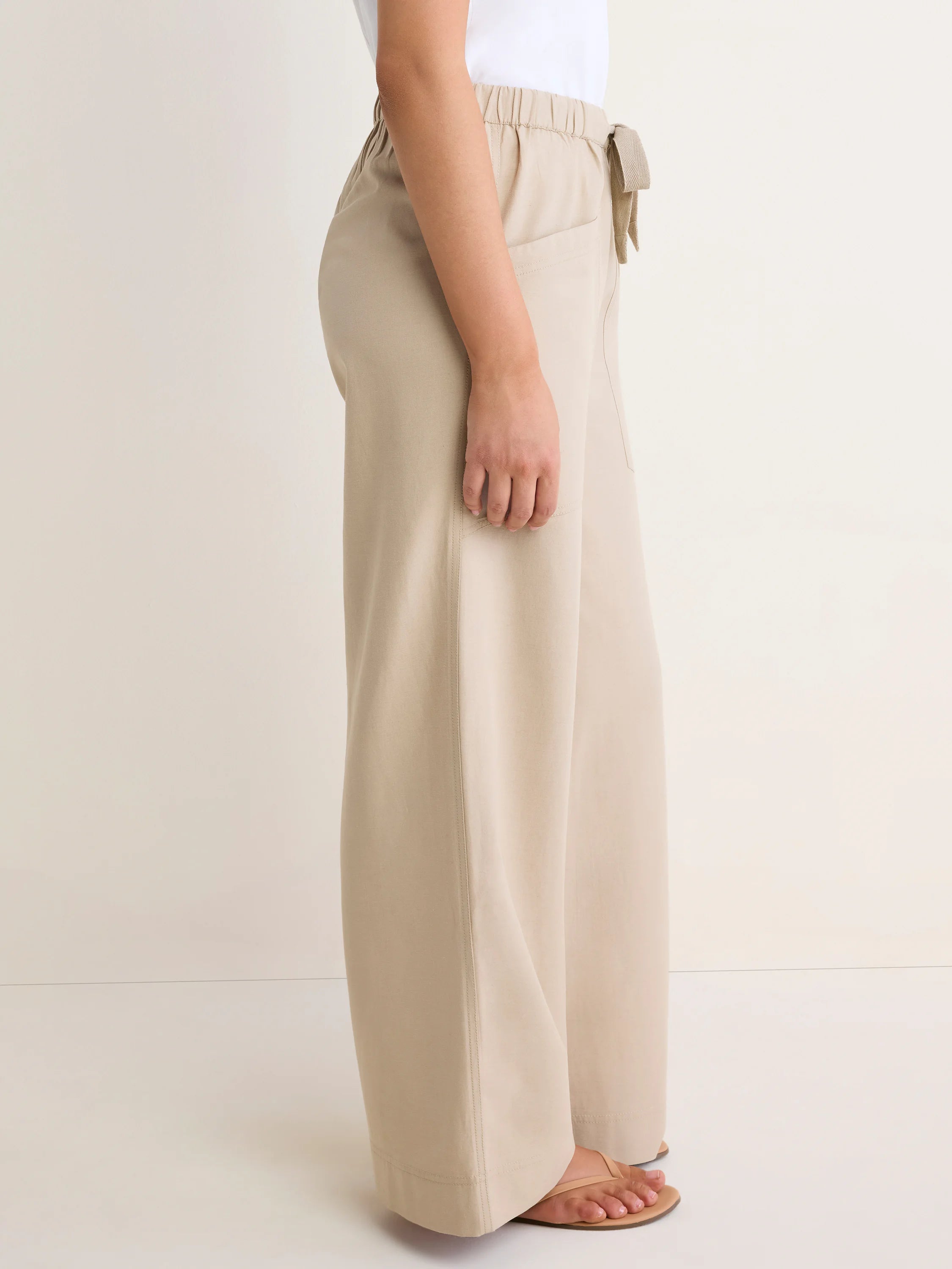 Light tan wide-leg pants with an elastic waist, a tie detail on the right, and side pockets.