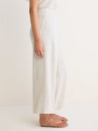 Oatmeal linen blend wide-leg pants, high-waisted and full-length, with visible fabric texture.