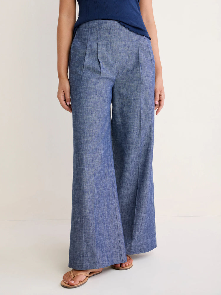 Blue chambray Ellis trousers. High-waisted with front pleats and wide, full-length legs.