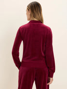 Deep red velour pullover, seen from back. Features mock neck, long sleeves with ribbed cuffs & hem.