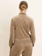 Back view of a camel velour pullover with a high stand-up collar and a ribbed hem.
