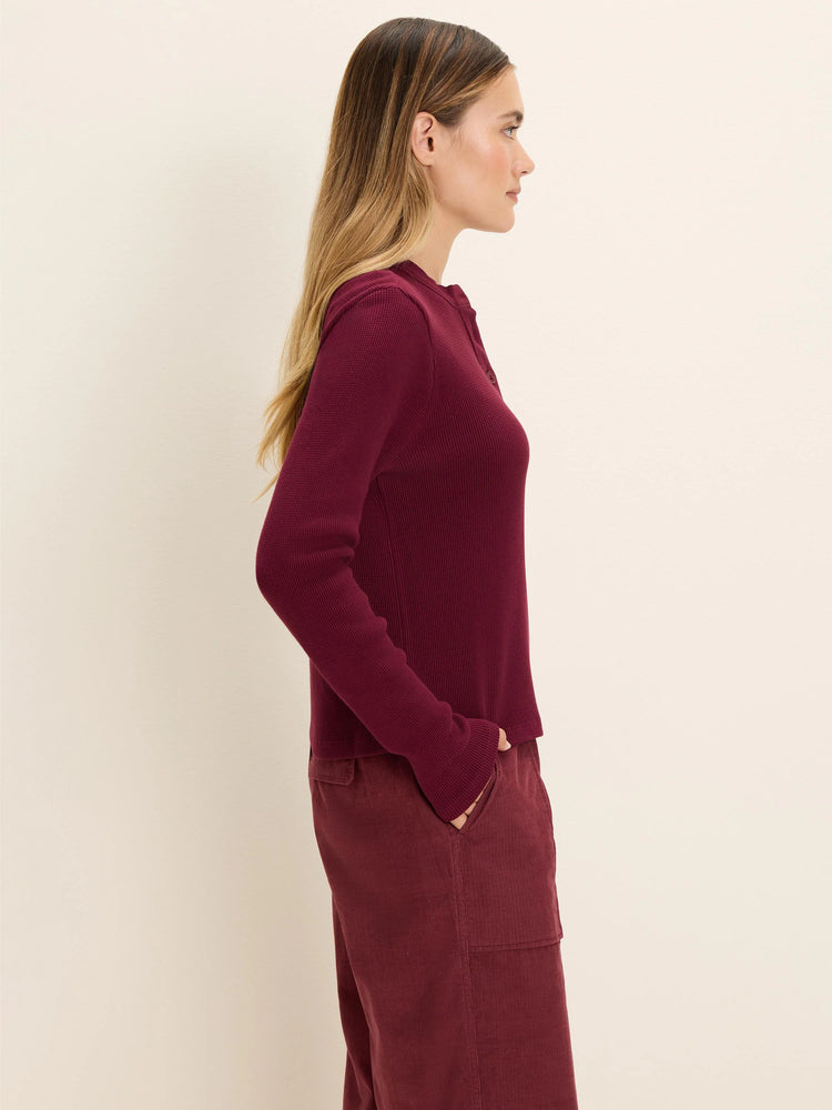 Deep red thermal waffle knit Henley top with long sleeves and a button placket.