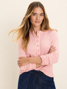 Light pink waffle knit thermal Henley top with button placket and ribbed cuffs.