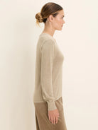 Light beige scoop neck sweater with long sleeves and ribbed cuffs.