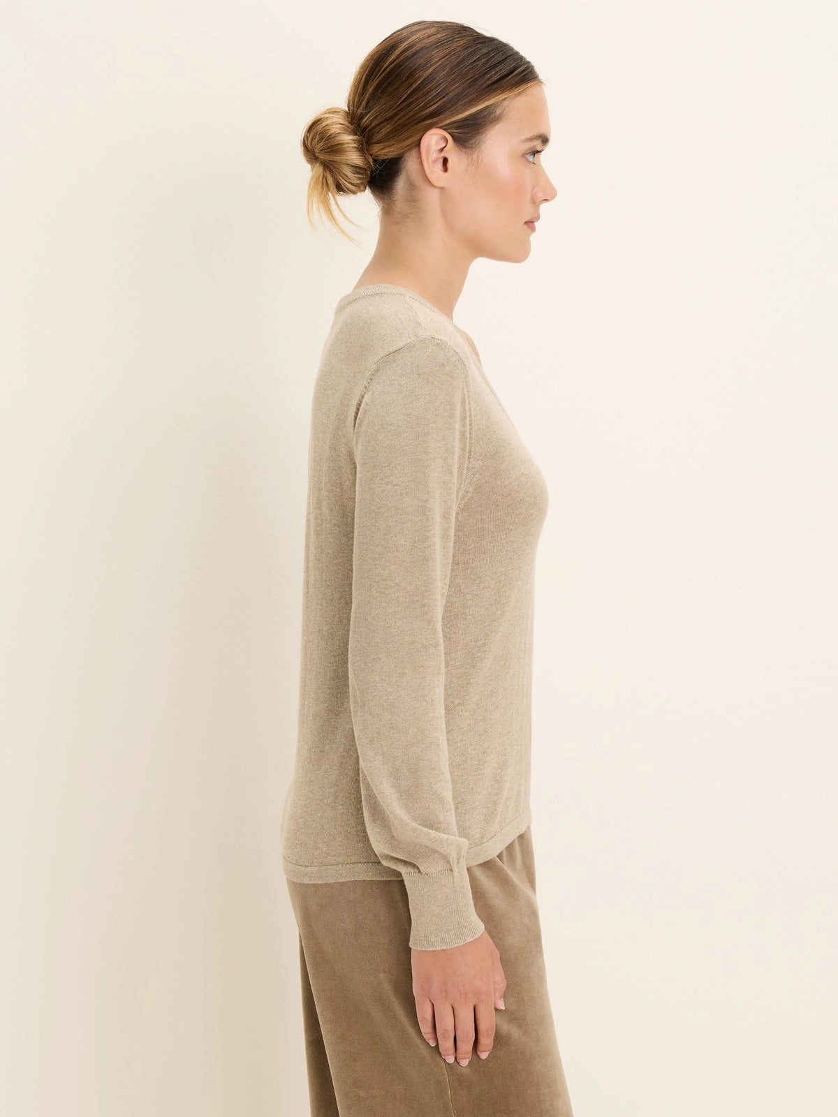 Light beige scoop neck sweater with long sleeves and ribbed cuffs.
