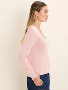 Light pink, fine-knit V-neck sweater with long sleeves on a model, seen from the side.