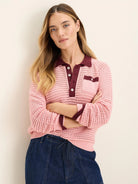 Pink mesh long-sleeve polo sweater with burgundy collar, button placket, and pocket trim. Features open knit texture.