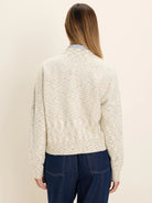 Back view of a slouchy off-white cardigan with multi-colored speckles, ribbed cuffs and hem.