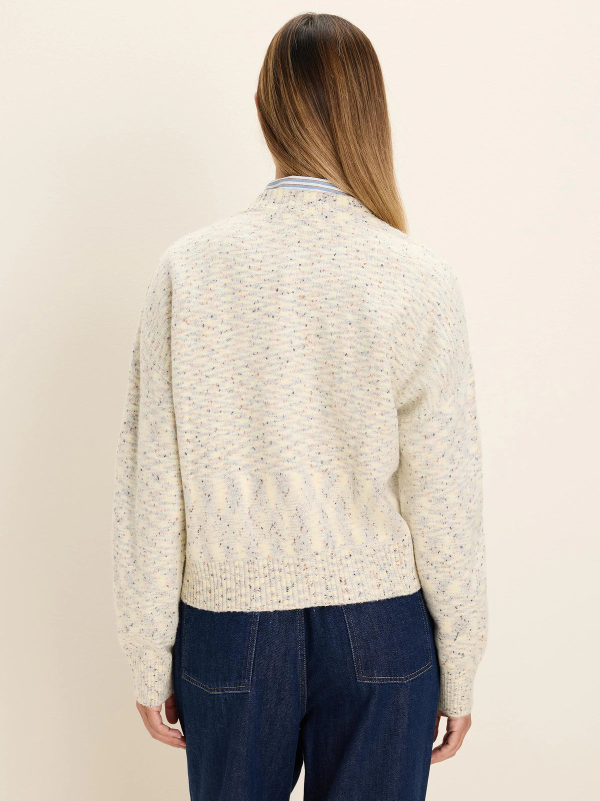 Back view of a slouchy off-white cardigan with multi-colored speckles, ribbed cuffs and hem.