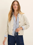 Cream knit cardigan with multicolored specks, relaxed fit, and round brown buttons.