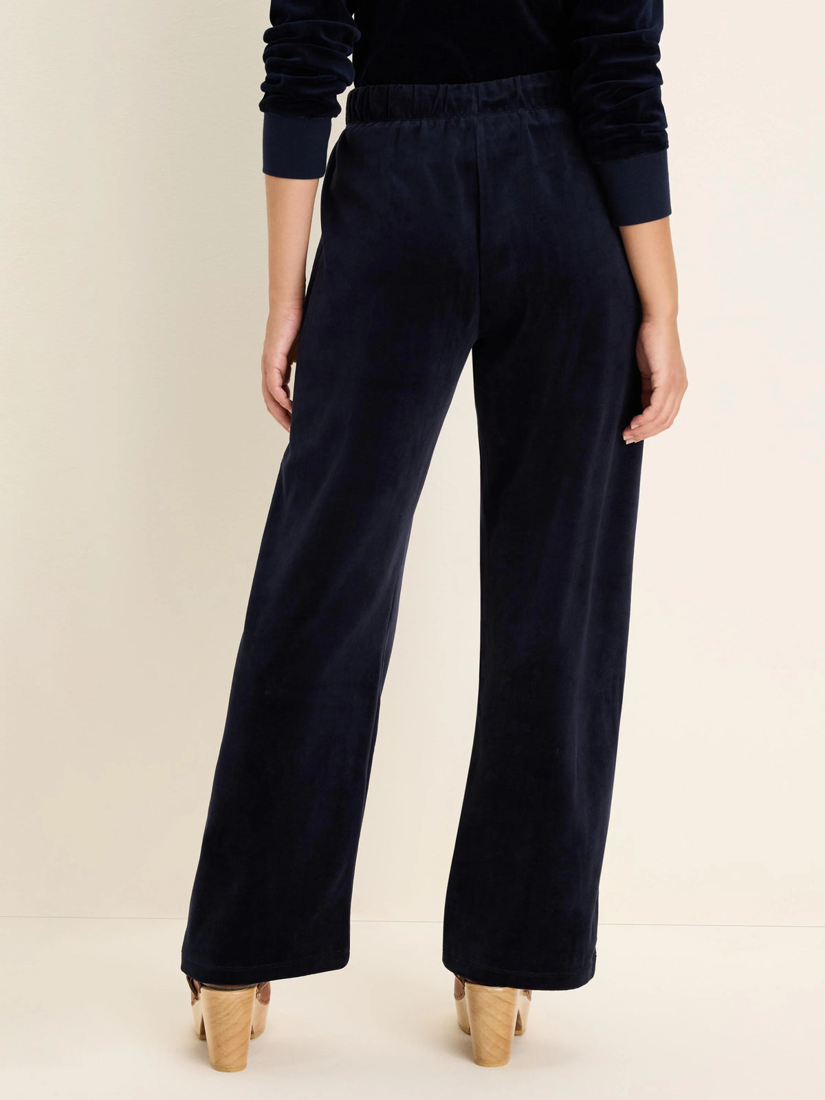 Dark blue velour wide-leg pants with an elastic waist, seen from behind on a model.