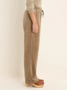 Side view of taupe velour pants. Features an elastic drawstring waist and a relaxed straight leg.