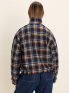 Navy plaid jacket with tan & off-white lines, high collar, elastic hem, seen from back.