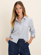 Collared shirt with vertical stripes in light blue, white, and thin beige.