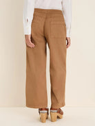 Back view of camel wide-leg denim ankle pants with an elastic waist and two rear patch pockets.