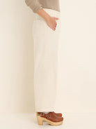 Cream denim ankle pants: elastic waist, side pockets, relaxed straight leg.