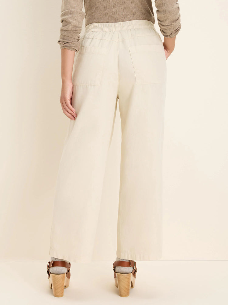 Rear view of cream wide-leg denim ankle pants with an elastic waist and back patch pockets.
