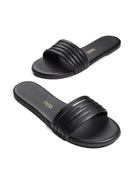 Black leather slide sandals with five parallel straps across the vamp.  The Tkees logo is visible on the insole.