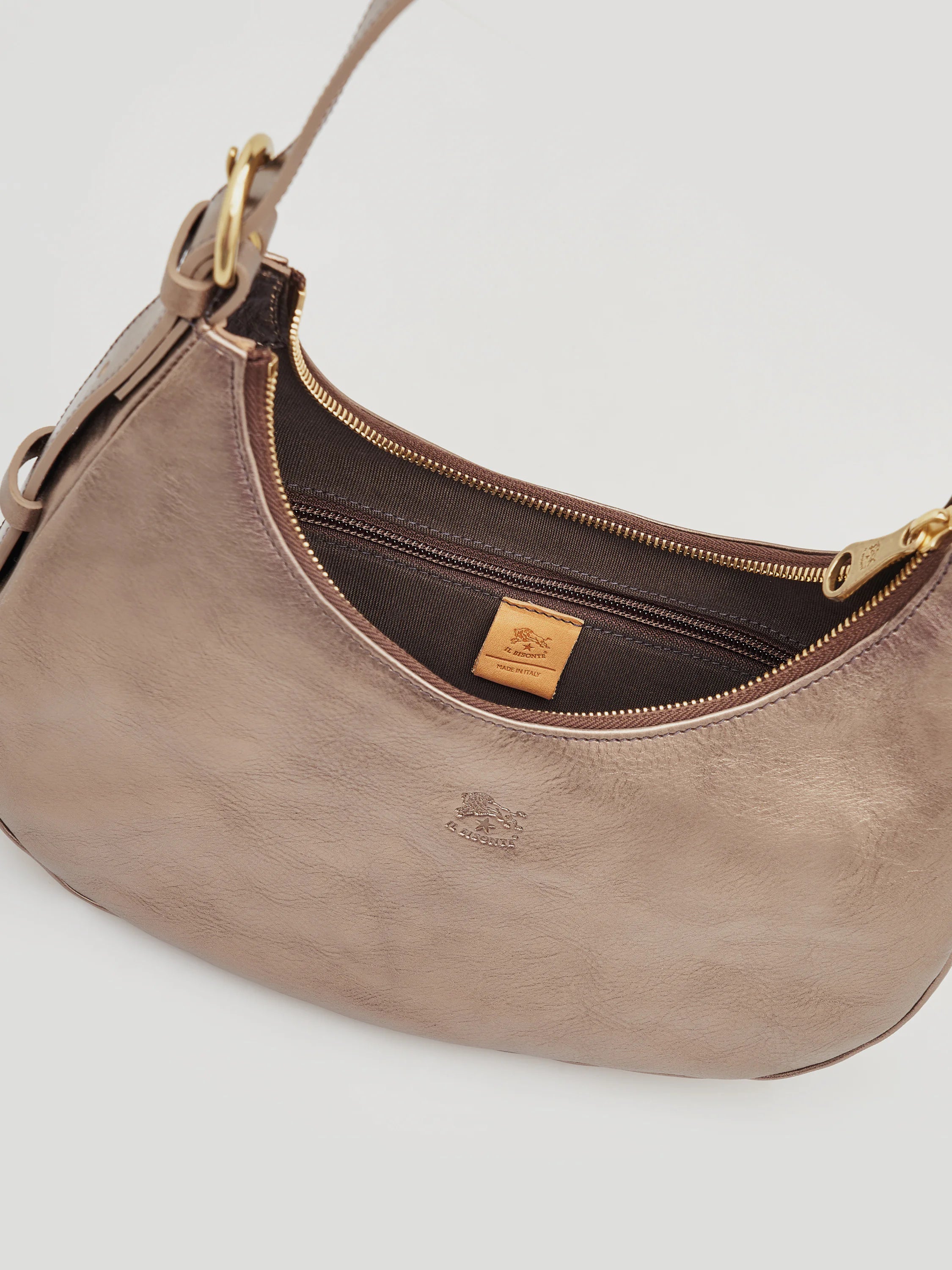 Small, curved, metallic taupe leather shoulder bag; gold zipper, dark brown lining, and embossed logo.