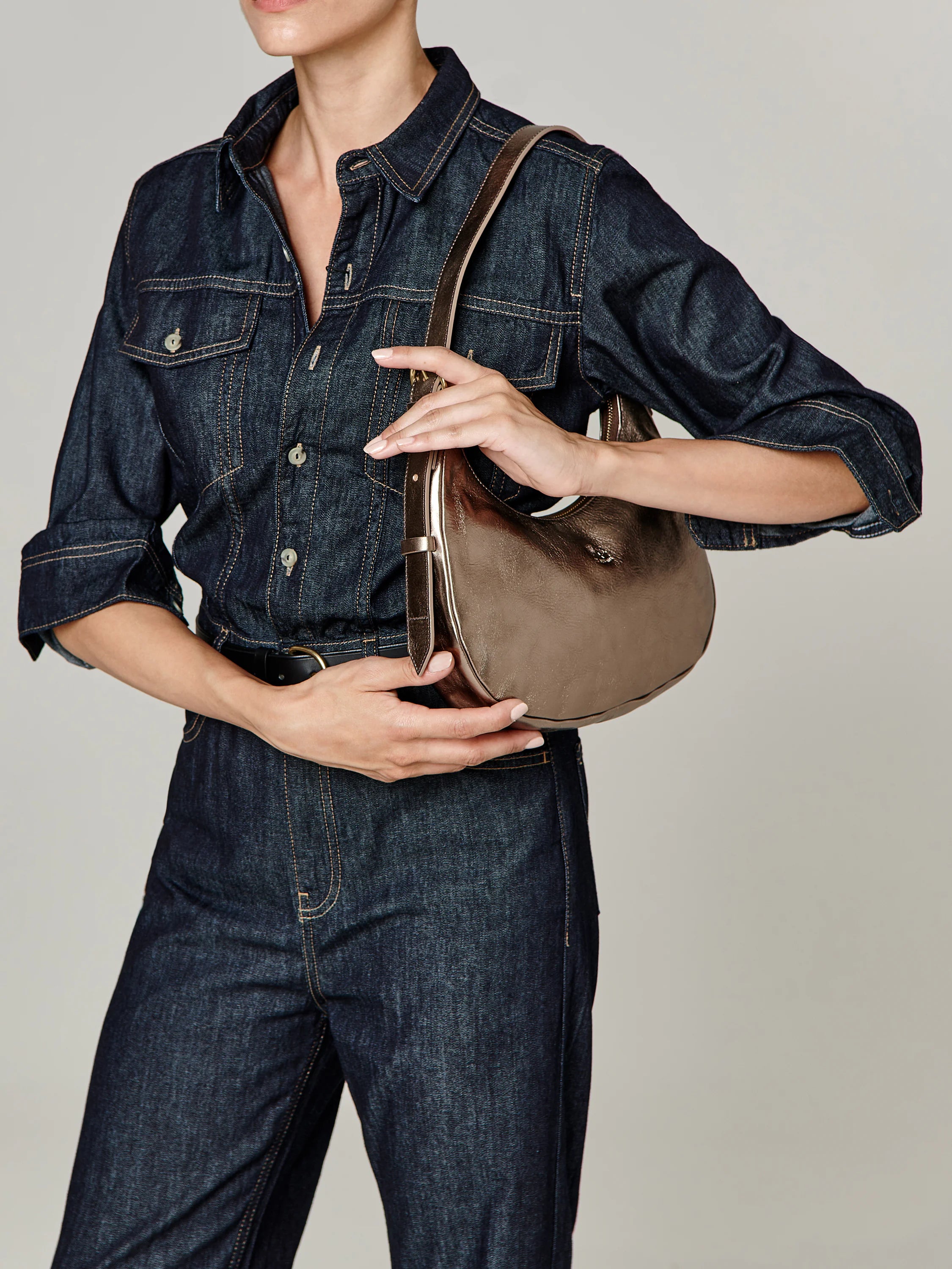 Small metallic bronze, smooth curved shoulder bag with a matching strap.