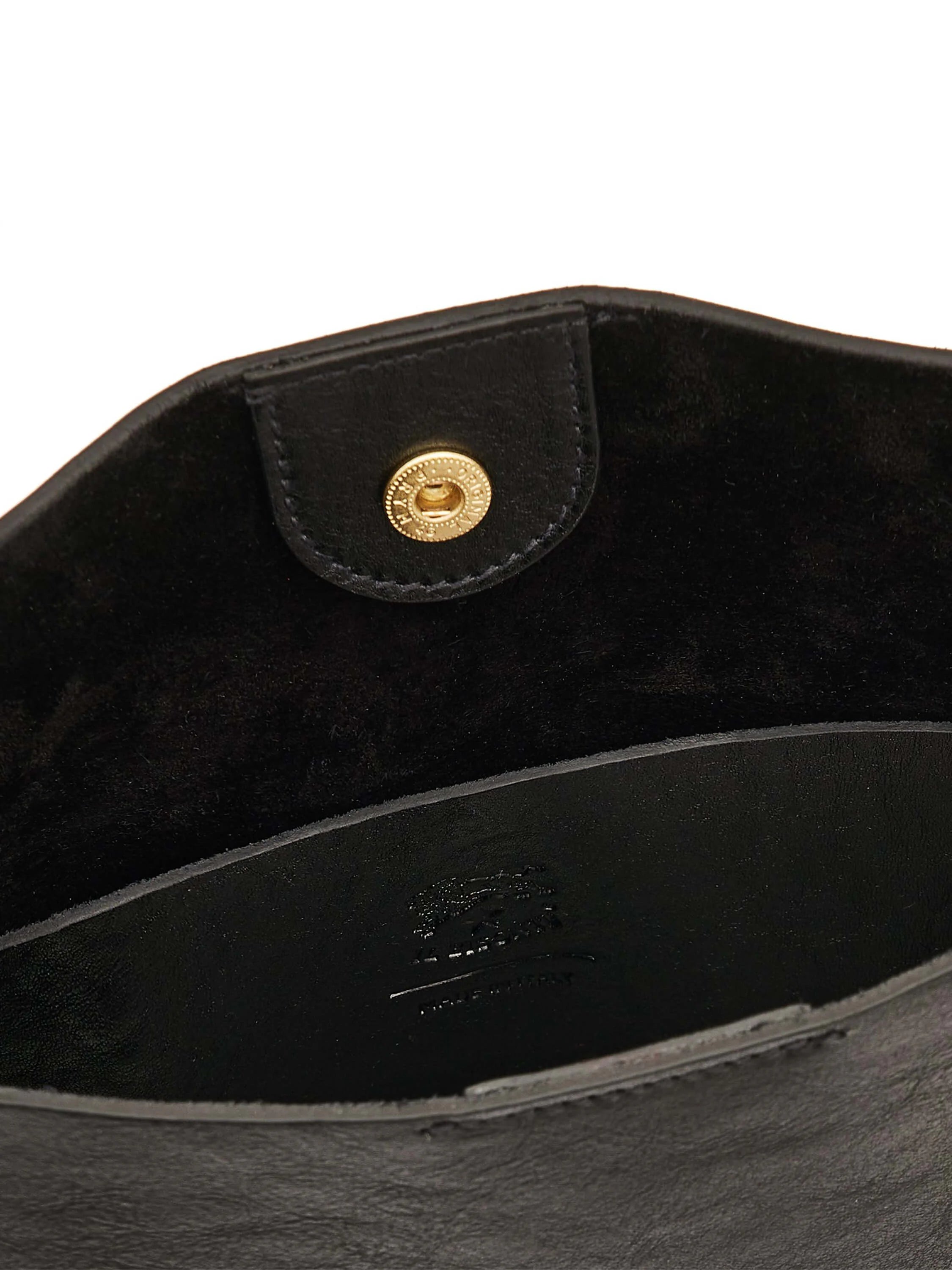 Black leather bag interior with gold snap closure on flap. Features black suede lining and an embossed logo.
