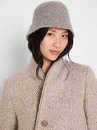 Light grey bucket hat with a chunky, textured wool-like surface, worn by a model.