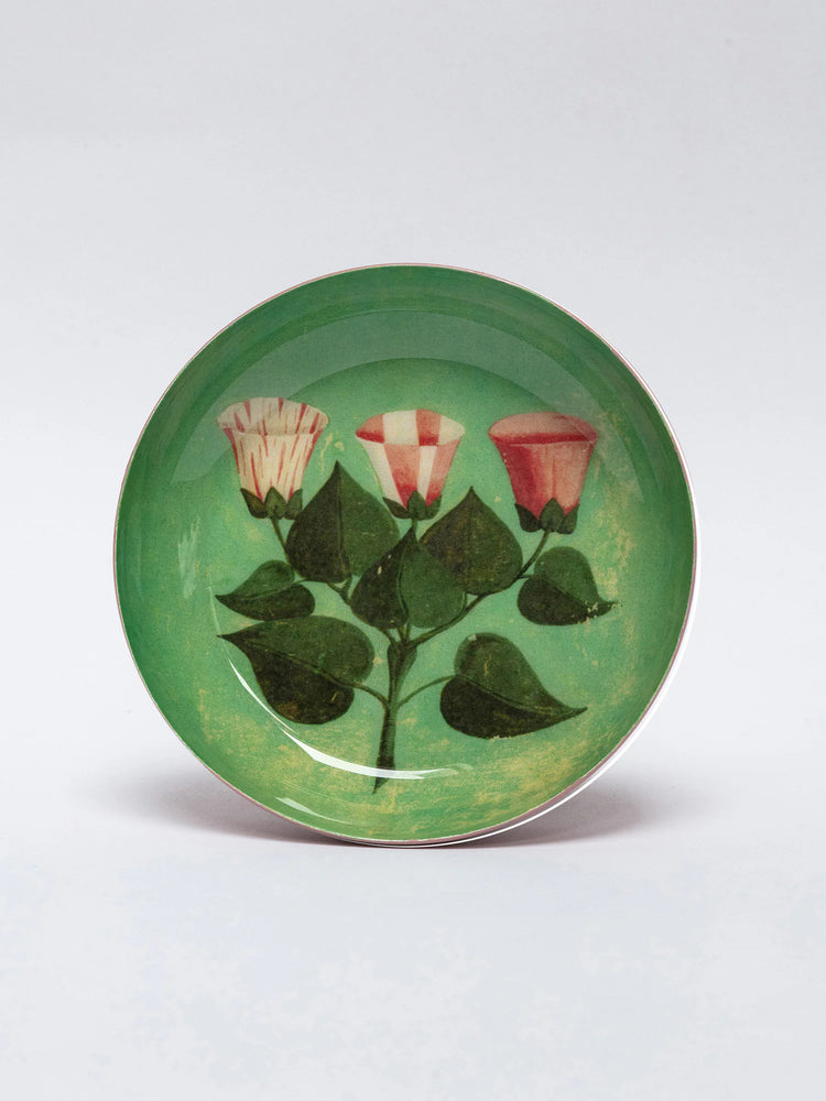 Round green tray with 3 stylized bell flowers: one striped, one checkered, one solid pink. Dark green leaves & stem.