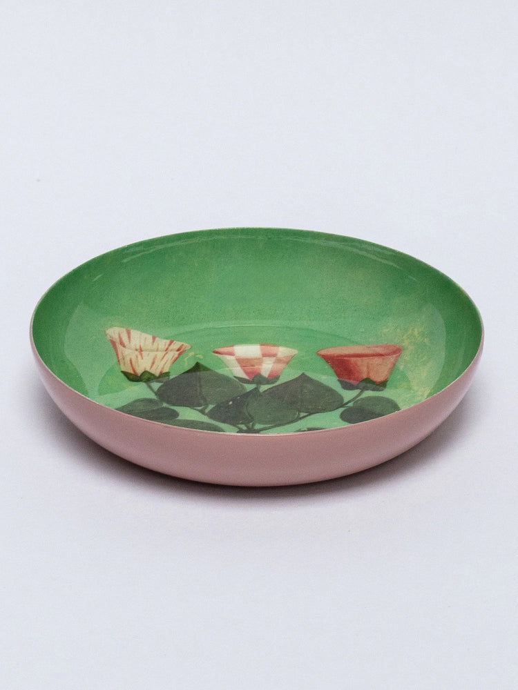 Round tray with pink exterior and green interior. Inside, three stylized flowers (striped, checkered, solid orange/red)...