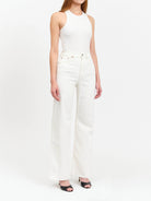 Off-white, wide-leg jeans; frayed hem.  Model wears a white top and black heels.