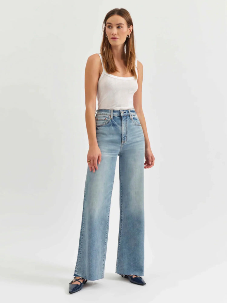 Light wash, high-waisted wide-leg jeans.  Raw hem. Model wears white top and dark blue shoes.